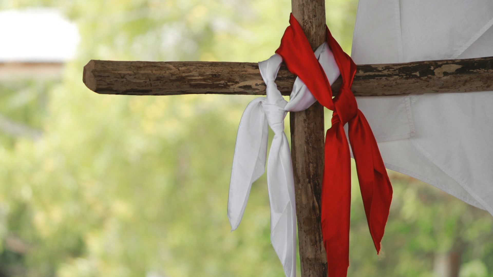 lenço vermelho e lenço branco pendurados em uma cruz de madeira